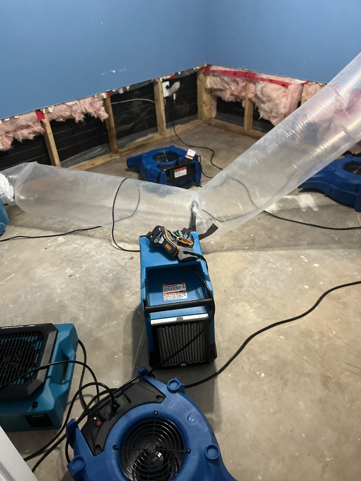 Dehumidifier and air movers running in a room with the lower drywall removed